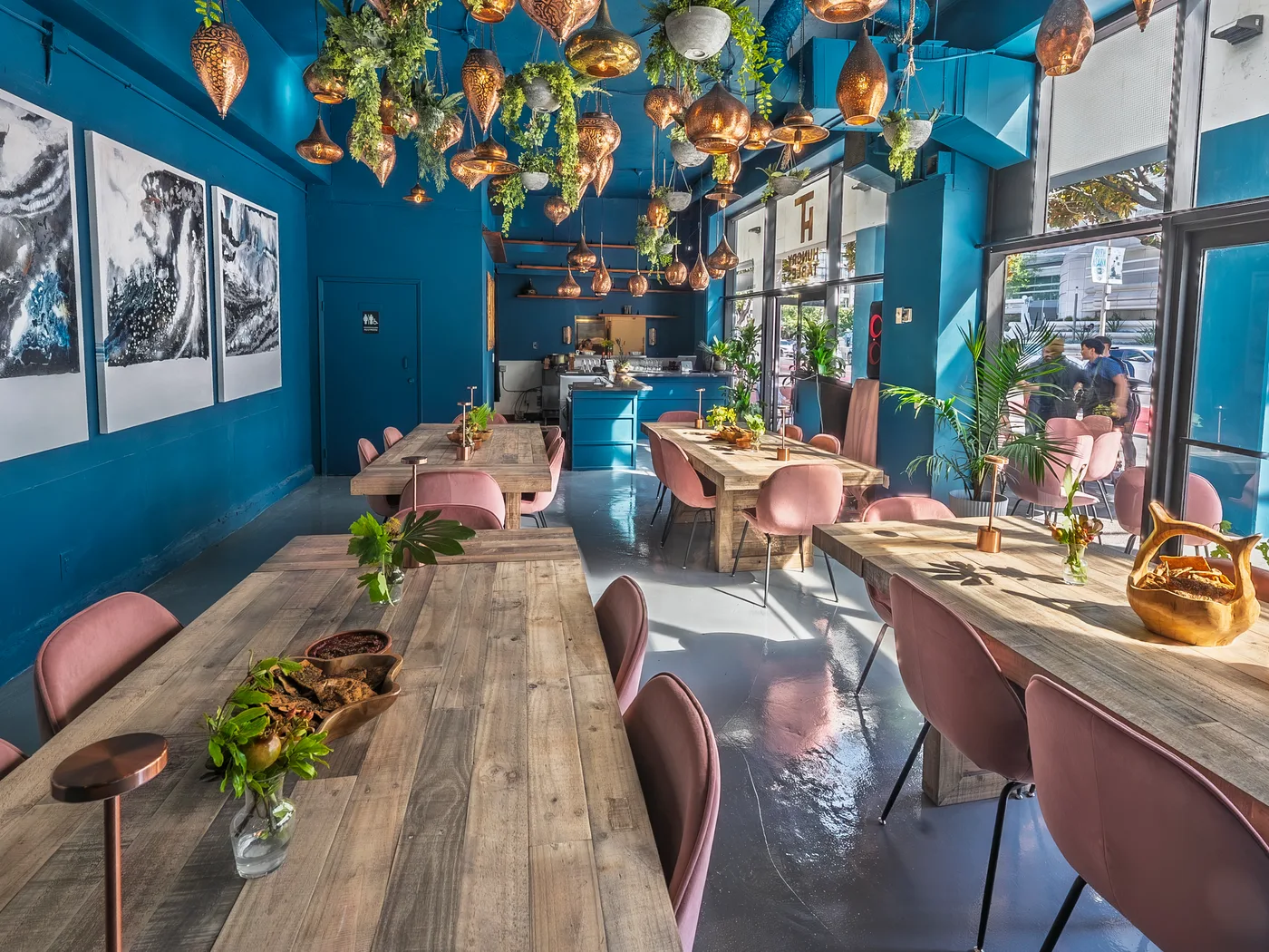 The communal table running the length of the room, set for dinner beneath the copper lantern ceiling